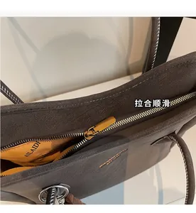 Detailed macro view of the golden metal zipper and dark brown textured leather tote bag