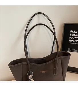 Detail view of large brown faux suede tote bag with gold logo and sturdy handles