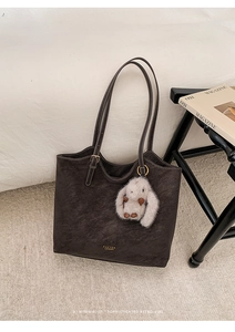 Detail of dark brown retro tote bag featuring a plush bunny charm and golden logo