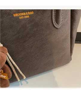 Close-up of vintage brown leather tote bag with gold logo and cute bear charm detail