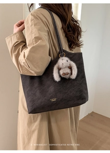 Detailed close-up of dark vintage tote bag with contrast stitching and rabbit charm
