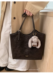 Deep coffee leather tote bag shown with a plush bunny charm on a model for retro style