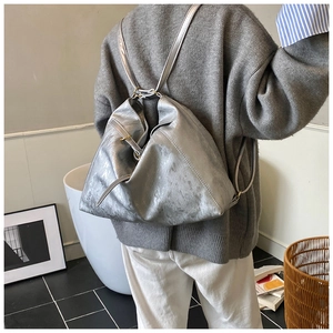 Detail of silver metallic tote bag with unique asymmetric fold and adjustable buckle
