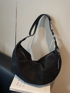 Large black suede crescent bag with sleek silver zippers and woven leather strap detail