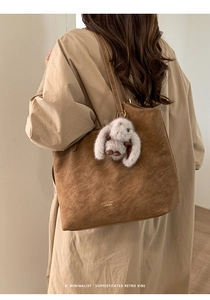Detail of brown suede tote bag with PAN'TOR LONDON logo and plush rabbit charm