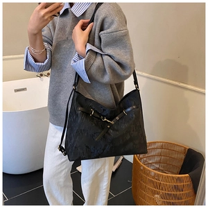 Detail of black jacquard tote bag with crossbody strap and golden hardware on shoulder