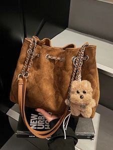 Brown quilted suede bucket bag with silver chain strap and plush dog charm accessory