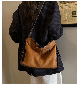 Detail of caramel suede tote bag with side pocket and adjustable leather strap on model