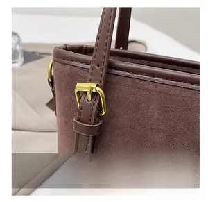 Detail of golden buckle and stitching on brown suede bucket bag with leather trim