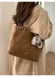 Detail of vintage brown suede tote bag with white stitching and plush rabbit charm