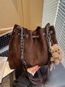 Brown faux suede bucket bag with quilted stitching and a cute dog pendant accessory