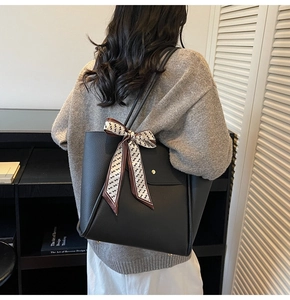Détail du cabas en cuir grainé noir avec un foulard en soie imprimé sur la bandoulière