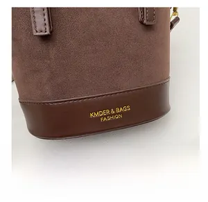 Detail showing contrast suede stitching and gold lettering on a vintage bucket bag