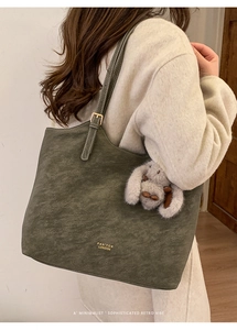 Detail of vintage olive green tote bag with adjustable strap and plush rabbit charm