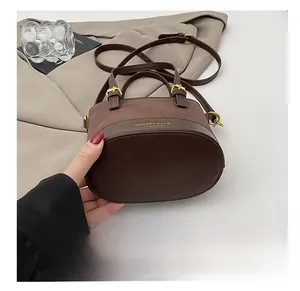 Detail showing high-quality contrast texture and gold logo on the brown bucket bag