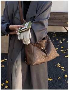 Close-up of dark brown tote bag with metallic texture and vintage golden hardware details