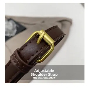 Detail of adjustable dark brown leather shoulder strap with golden metal buckle for bucket bag