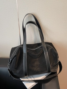 Large black leather travel tote bag with contrast white stitching and wide shoulder strap
