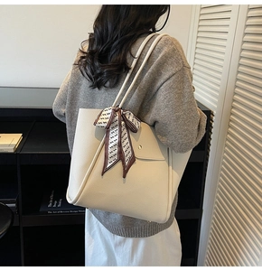 Détail du sac cabas blanc cassé avec texture grainée et foulard en soie sur la poignée