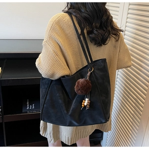 Dettaglio di una borsa tote nera grande con ciondolo in pelliccia e perline di legno
