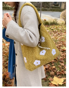 Close-up of yellow plush tote bag with white floral embroidery and soft knit texture
