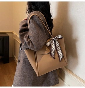Gros plan d'un sac cabas camel avec poignée en foulard de soie et rivet métallique décoratif
