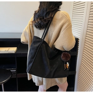 Dettaglio della borsa tote vintage nera con ciondoli decorativi indossata a spalla
