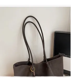 Macro detail of dark brown tote bag with matte texture and golden metallic rings