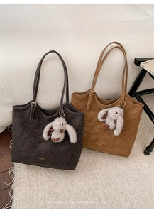 Detail of vintage tote bags in coffee and caramel with plush bunny charms on a soft rug