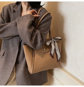 Sac fourre-tout en cuir grainé kaki avec foulard et boucle dorée porté par un mannequin