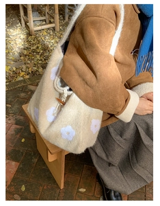 Detail of plush bucket bag with floral embroidery and toggle closure in autumn outdoor setting