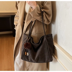 Détail du grand sac cabas en daim marron café avec pompon et surpiqûres blanches contrastées