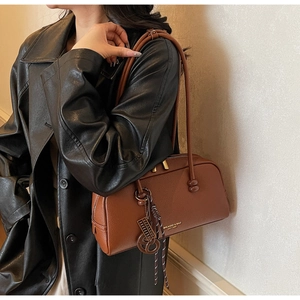 Detail of brown litchi pattern leather shoulder bag with gold zipper and charms