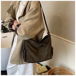 Detail of dark olive suede shoulder bag with stitching and metallic buckle on model