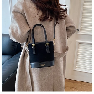 Detail of minimalist black bucket bag with gold lettering and high-quality hardware