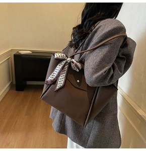 Détail d'un sac cabas en cuir marron à motif litchi avec foulard en soie et boucle argent