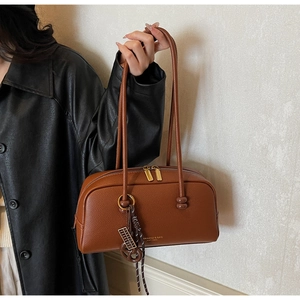 Detailed view of brown litchi pattern leather bag with gold hardware and logo