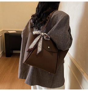 Sac cabas en cuir marron avec foulard en soie porté par un mannequin dans un bureau