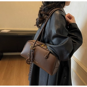 Brown lychee leather bowling bag featuring dual zippers and knotted rope pendant