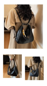 Macro shot of versatile black PU leather dumpling tote bag with beaded tassel and adjustable straps