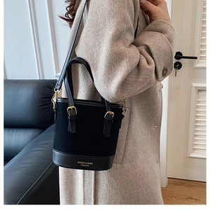 Detail of black contrast texture bucket bag with gold hardware and logo branding