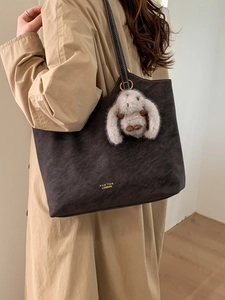 Vintage large capacity dark grey tote bag with rabbit charm shown on a beige coat model