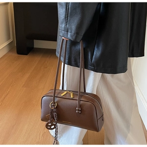 Brown litchi grain leather bowling bag detail with gold zipper and dual shoulder straps