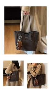 Close-up of charcoal black tote bag with shoulder straps and plush bear charm detail