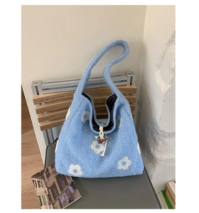 Close-up of light blue plush tote bag featuring white floral embroidery and horn button