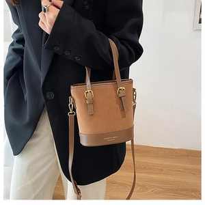 Detailed view of caramel suede bucket bag with leather trim and gold-tone hardware accessories