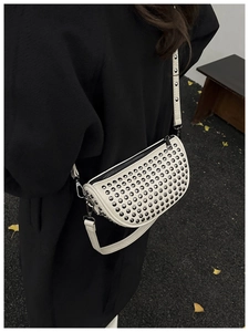 White rivet crescent crossbody bag worn over a black wool coat showing fashion size