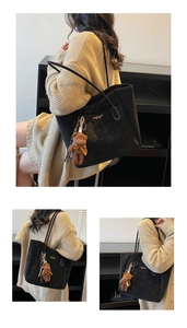 Detail view of large black suede tote bag with contrast stitching and teddy bear charm