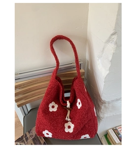 Detail of red plush tote bag showing white flower embroidery and wooden toggle closure