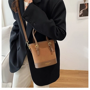 Detail showing brown bucket bag with mixed textures, logo print and gold hardware